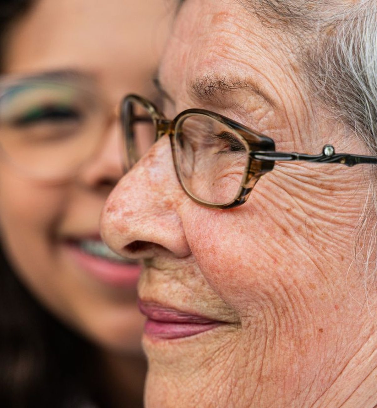 A caregiver and a smiling older woman sharing a warm, tender moment