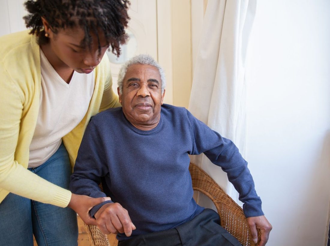 A smiling caregiver assisting an older man at home
