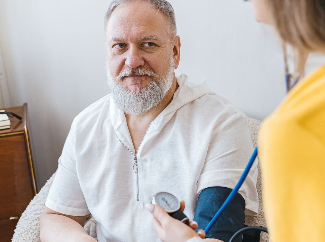 A nurse checking an older man's blood pressure at home
